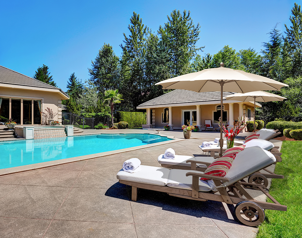 FiberBuilt Terrace Umbrellas Great backyard with swimming pool and lounge chairs in American Suburban luxury house. Northwest USA